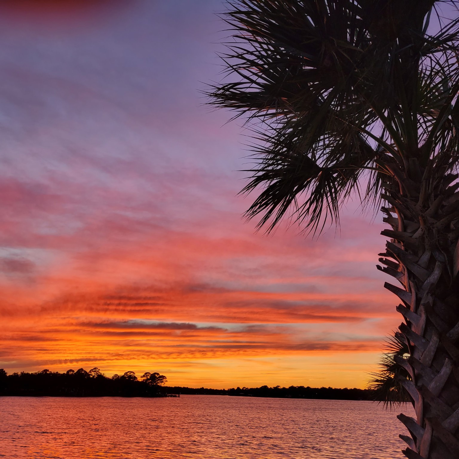 A vivid orange, pink, and purple sunset over the water